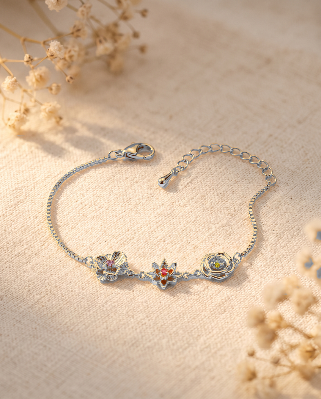 Silver-tone birth flower bracelet with three flower charms on cream linen.