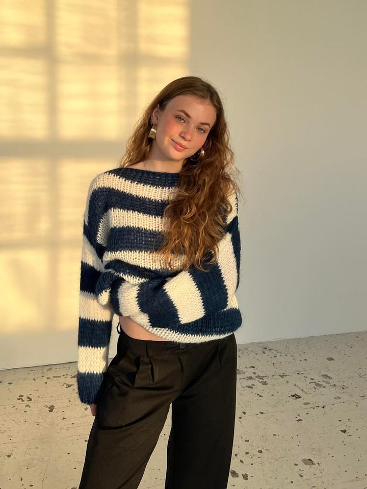 Junge Frau in gestreiftem Pullover, blau-weiß, lässig, modisch, Herbstmode, lange Haare.
