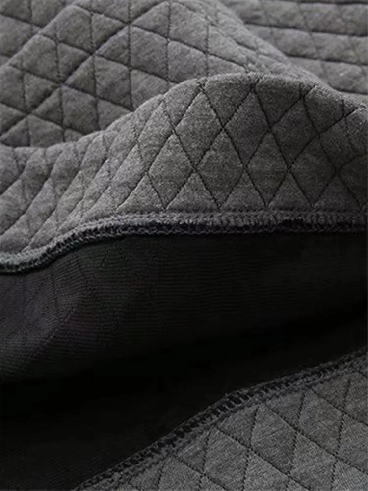 Grauer gesteppter Stoff, weiche Textur, ideal für Polster oder Decken.