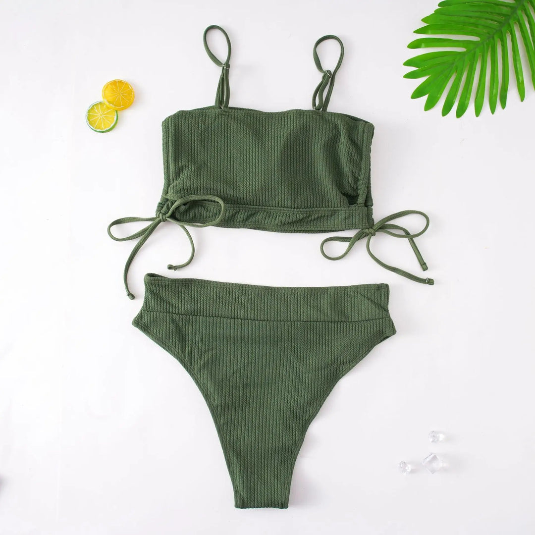 Grünes Bikini-Set mit Rippstruktur, Spaghetti-Trägern und seitlichen Bindebändern auf weißem Hintergrund.