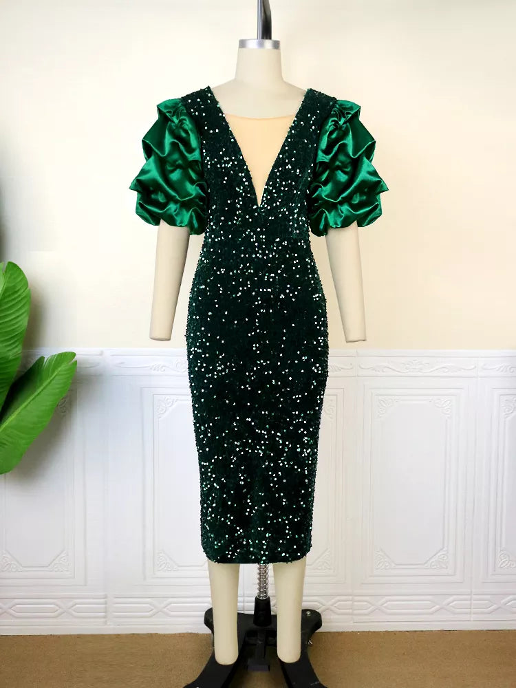 Grünes Paillettenkleid mit tiefem V-Ausschnitt und voluminösen Ärmeln auf Schneiderpuppe.