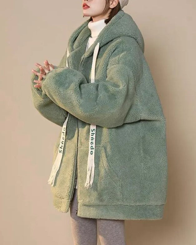 Frau in grüner Teddyjacke mit Kapuze, Wintermode, gemütlich, warm, stilvoll, Damenbekleidung.