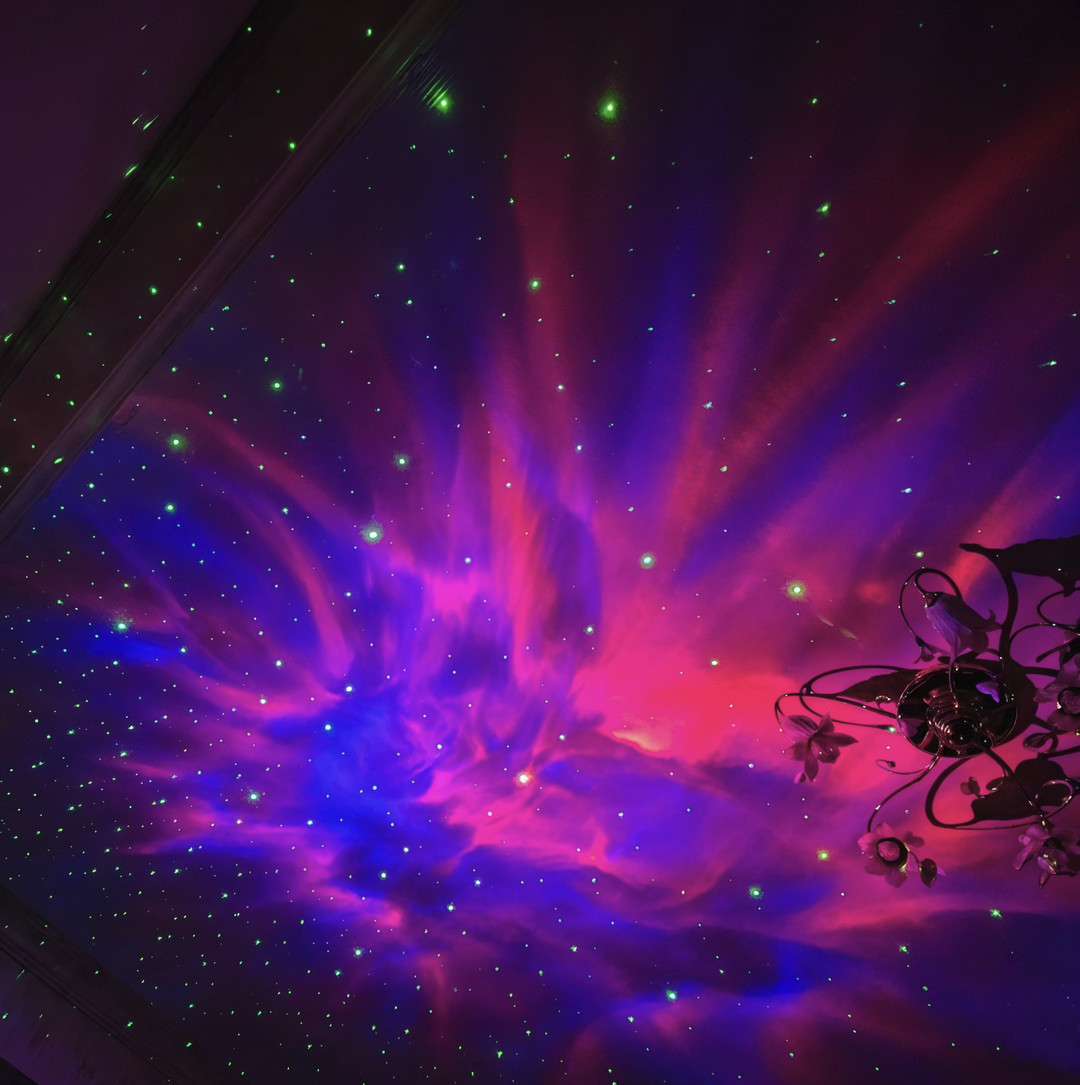 Vivid pink, purple and blue nebula with green stars projected on a ceiling.