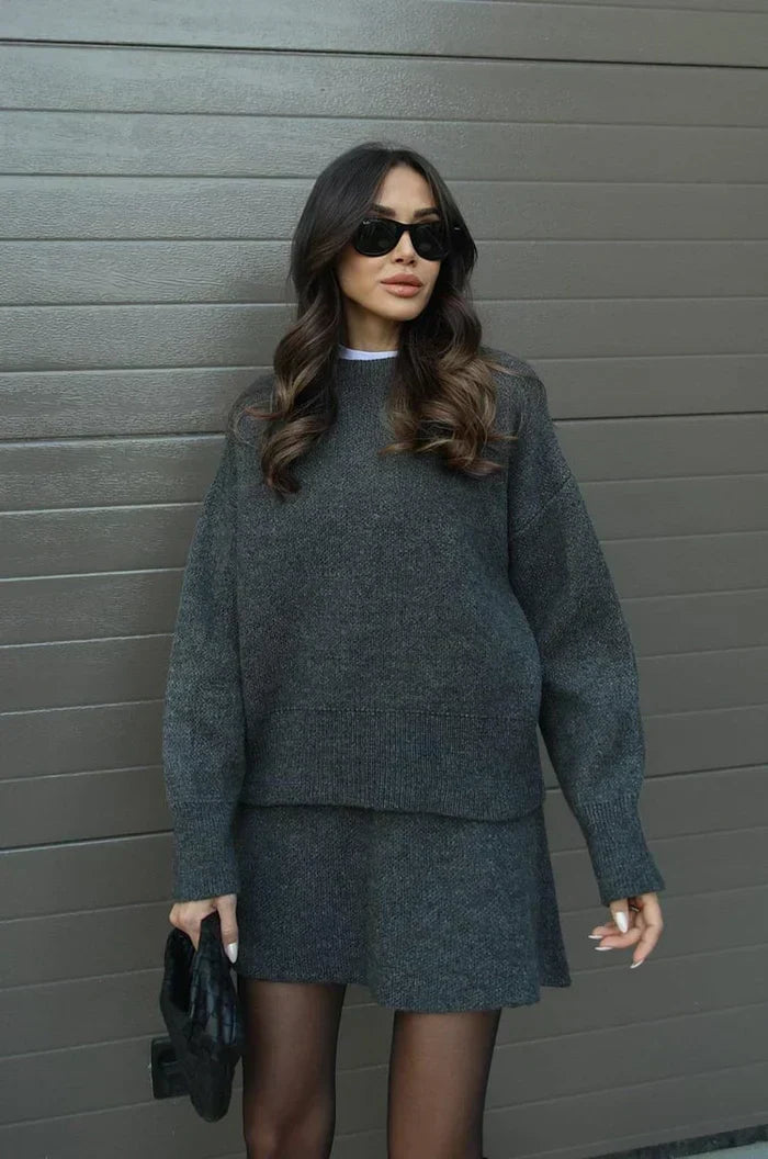 Charcoal gray two-piece knit set, front view, with ribbed cuffs and hem and a black clutch 12