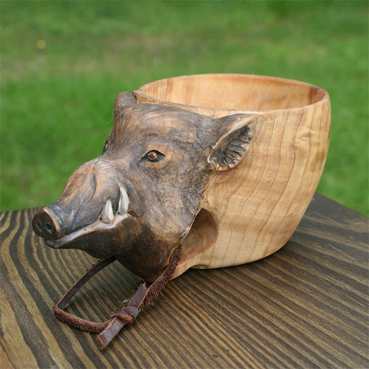 Handmade wooden cup detail with a wild boar head and a leather cord