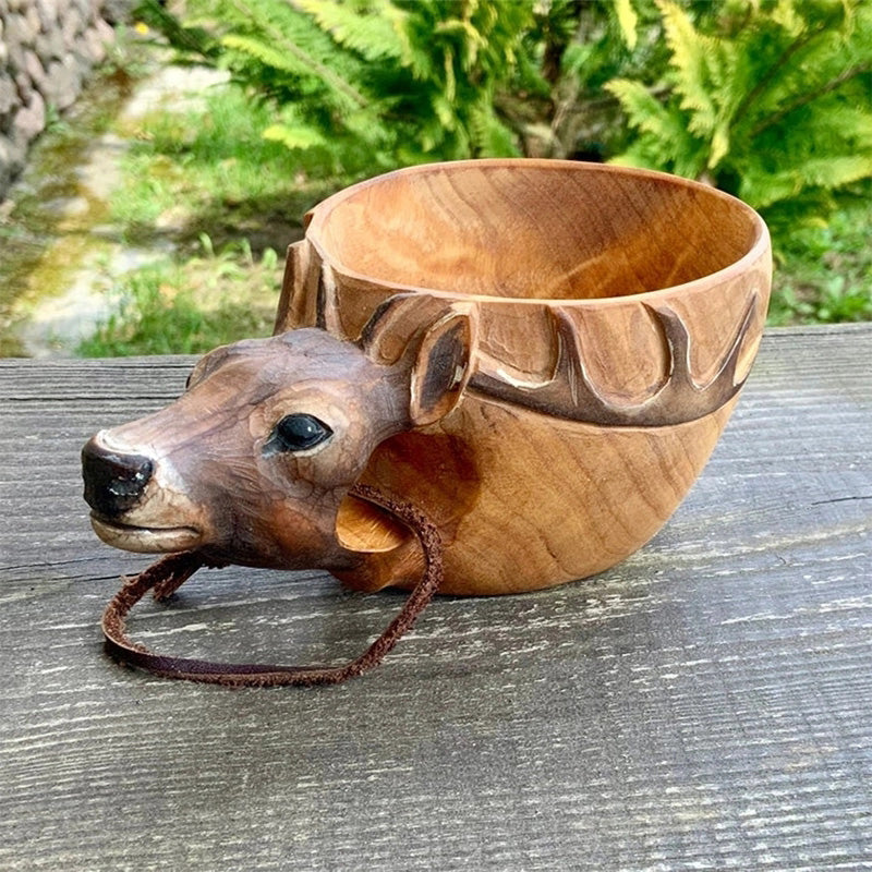 Handmade wooden cup detail with a deer or elk head and a leather cord