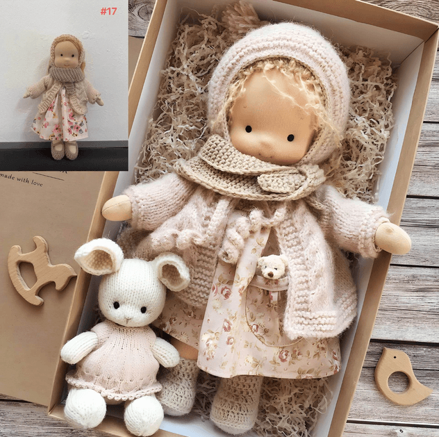 Doll in pale pink knit hood, cardigan and floral dress boxed with a white knitted bunny; inset shows doll standing 3