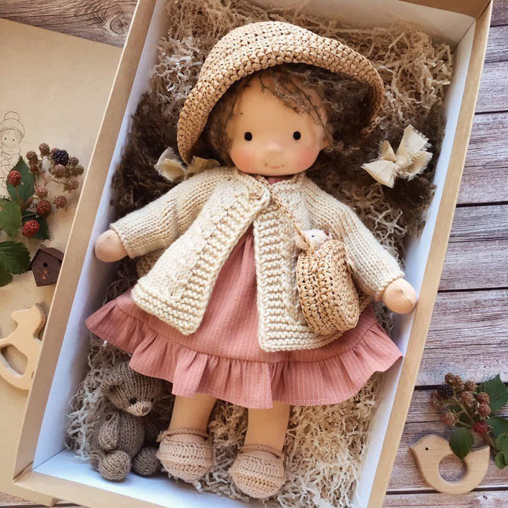 Doll with dark curly hair in a crocheted straw hat, cream cardigan and ruffled pink dress, boxed with a small knit bear 8