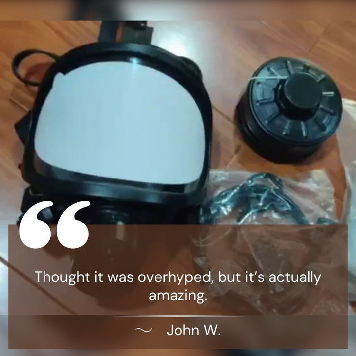 Black NBCR protective mask laid beside its separate filter canister and strap bag.