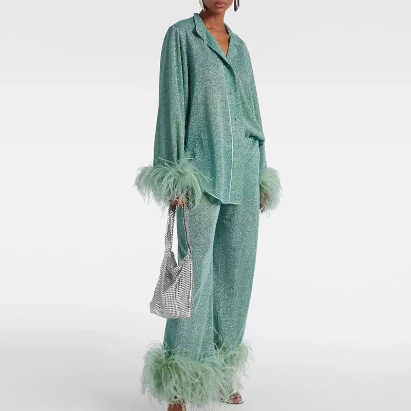Model in a mint-green glitter set with notch collar, feather cuffs and pant hems, carrying a silver mesh bag. 2