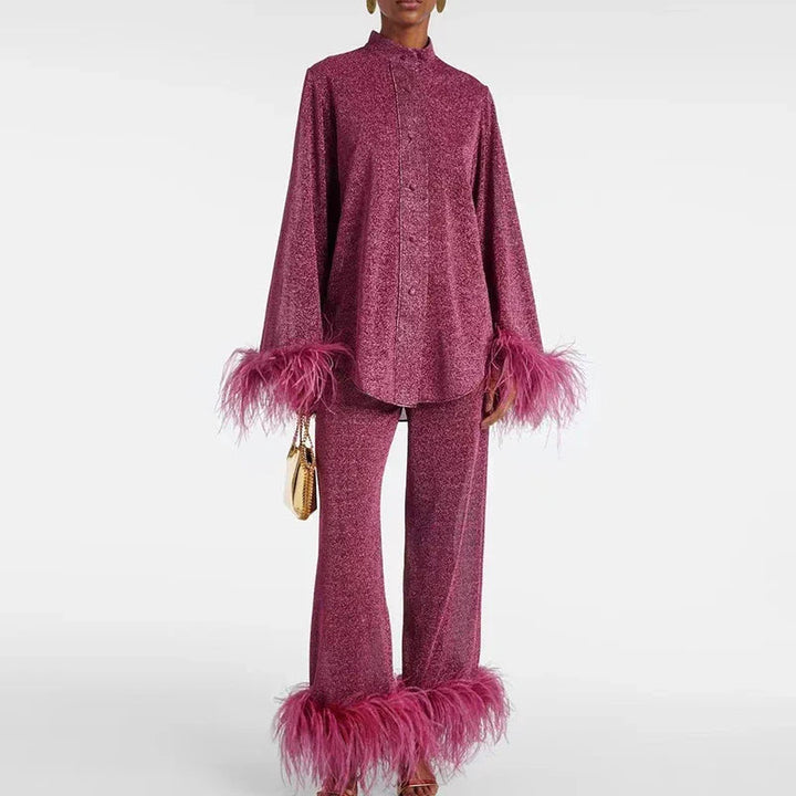 Model in a raspberry-pink glitter shirt and wide-leg pants with matching feather cuffs and hem, holding a small gold clutch. 1