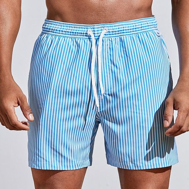 Model wearing light sky blue and white striped swim shorts with a white drawstring tied at the elastic waist, front view.