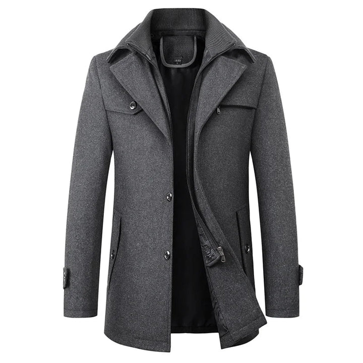 Front view of the gray version of the coat, showing the double collar, buttoned flap pocket and zip-through inner layer partly open. 2