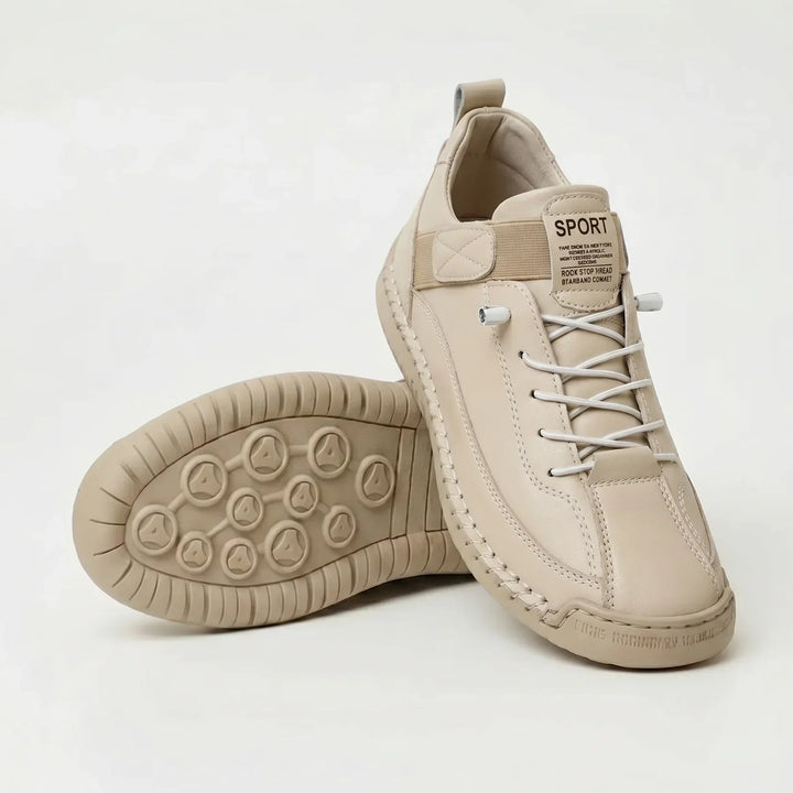 Cream-colored smooth sneakers with white elastic laces, one shoe upright and one displaying the matching sole 10