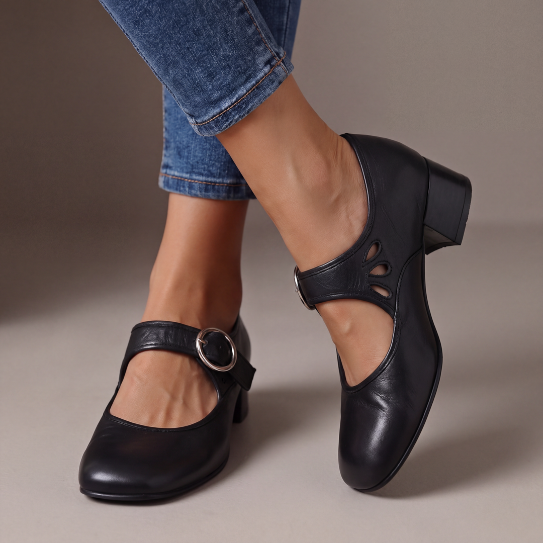 Blue leather block-heel pumps with a round silver buckle strap and teardrop cutouts, shown from the front.