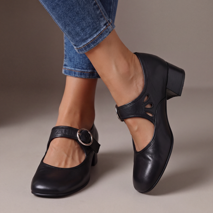 Blue leather block-heel pumps with a round silver buckle strap and teardrop cutouts, shown from the front.