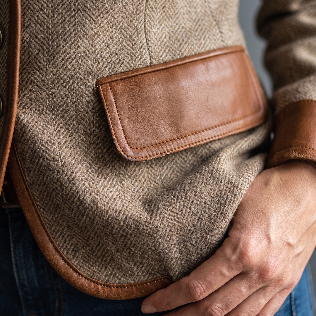 Detail of a stitched faux leather pocket flap and curved trimmed hem on the tweed 5
