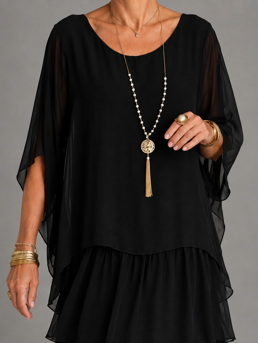 Close-up of the black dress bodice with sheer cape sleeves, scoop neckline and a pearl tassel necklace