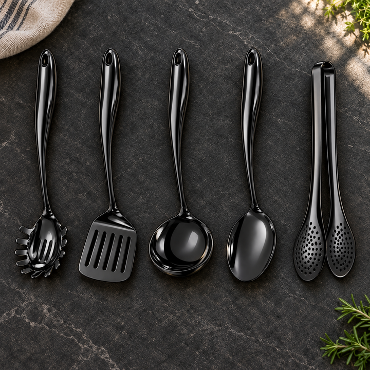 Five glossy black utensils in a row on dark stone: pasta server, slotted turner, ladle, solid spoon and perforated tongs, with herbs nearby. 28