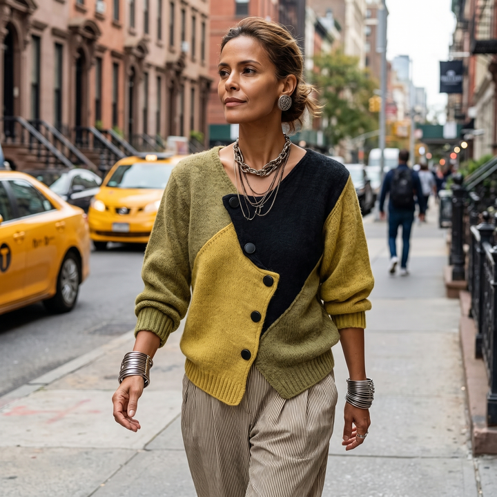 Model walking down a city street in the olive, mustard and black sweater with striped pants 4