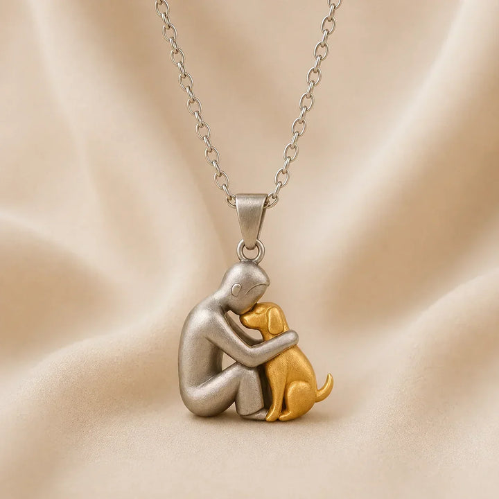 Side-profile pendant of a seated person pressing foreheads with a gold-tone dog, in matte silver tone on a chain. 6