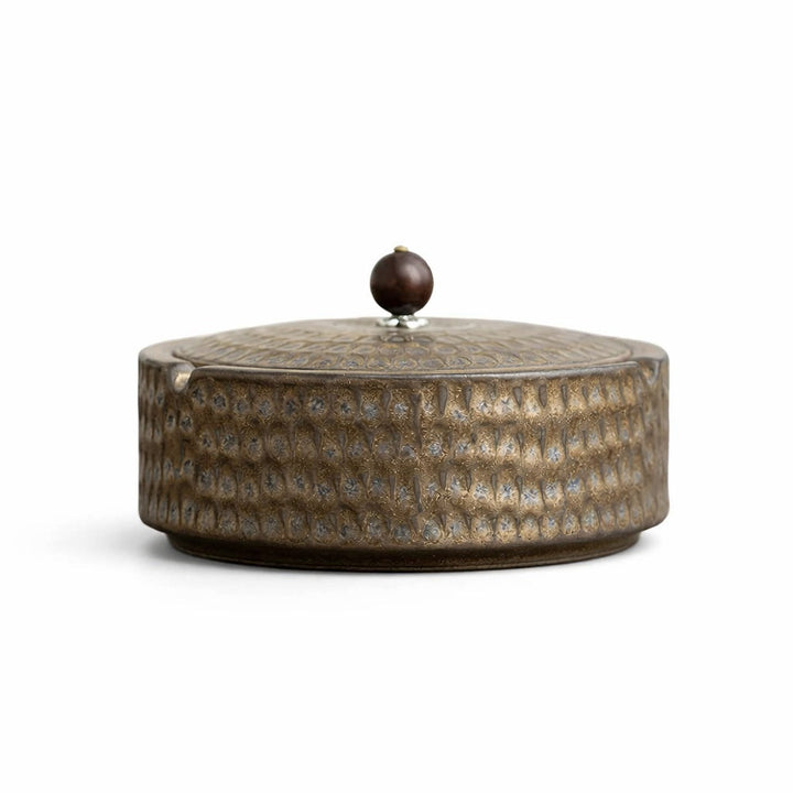 Side view of a bronze-brown ashtray with the lid on and a dark wooden knob.