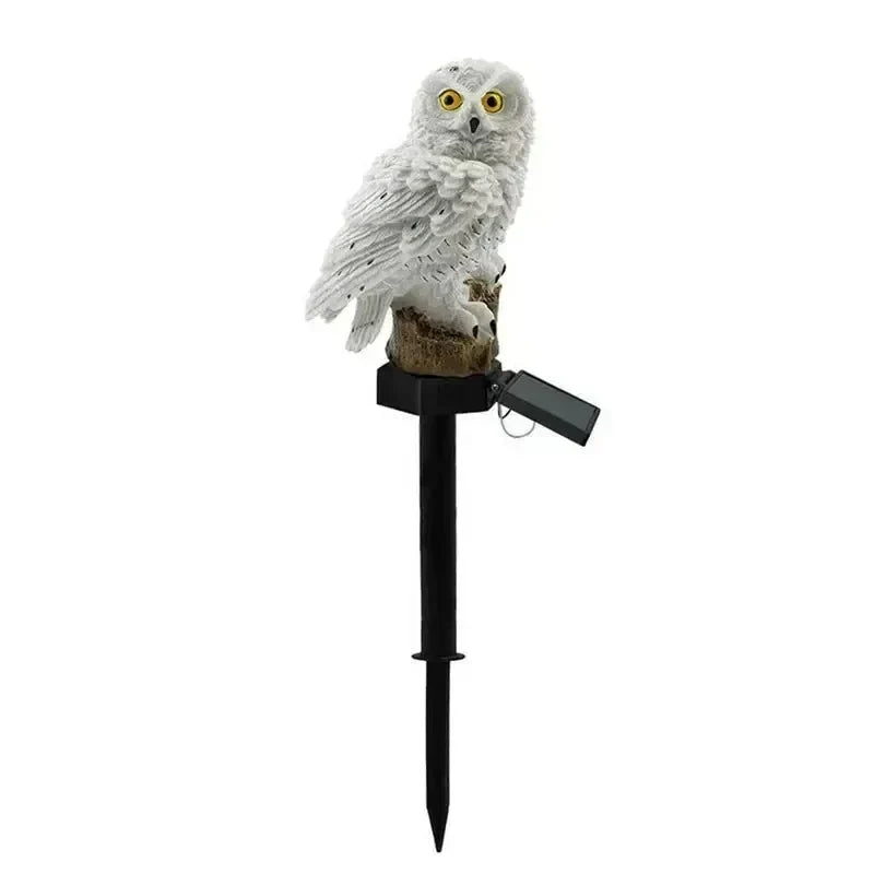 White owl light on a black ground stake with its solar panel angled out against a plain white background.