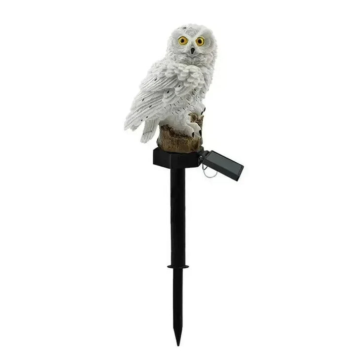 White owl light on a black ground stake with its solar panel angled out against a plain white background.