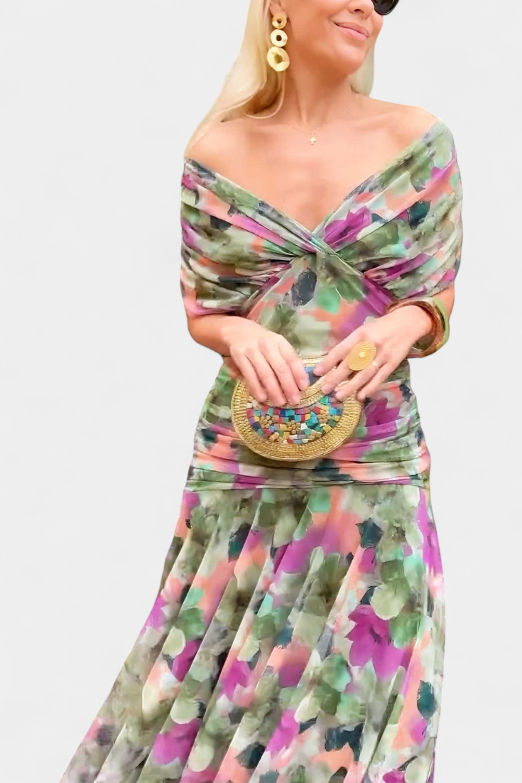 Close-up of the green, pink and purple printed dress with off-the-shoulder neckline, worn with gold earrings and a mosaic clutch. 10