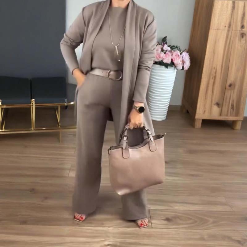 Woman in the taupe set with an open cardigan, belt and necklace.