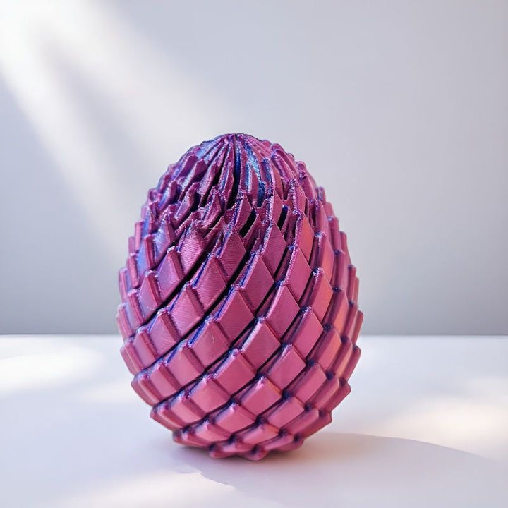 Pink and purple scaled egg on a white surface with soft window light 10