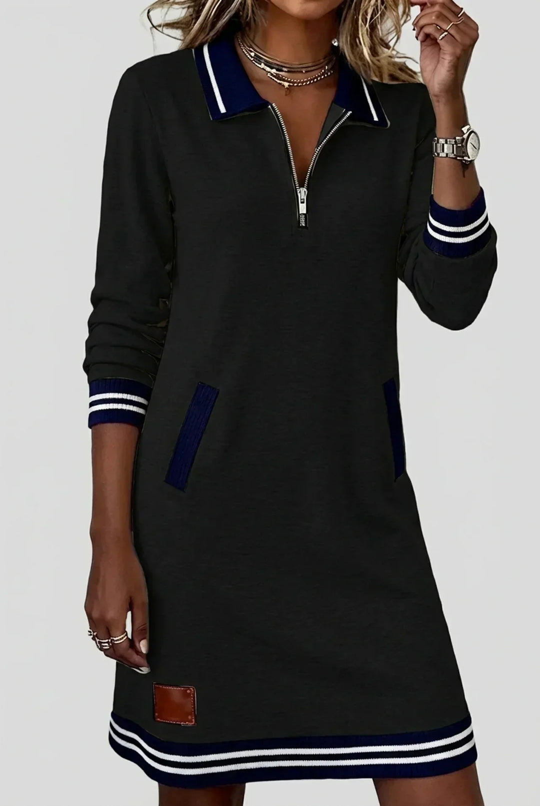 Model in the black dress with navy and white striped trim and a brown leather-look patch near the hem. 4