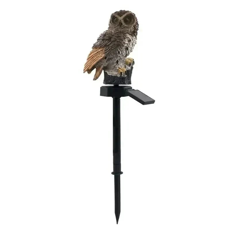 Brown owl light with orange-tan wing feathers on a black stake with a solar panel against a white background.