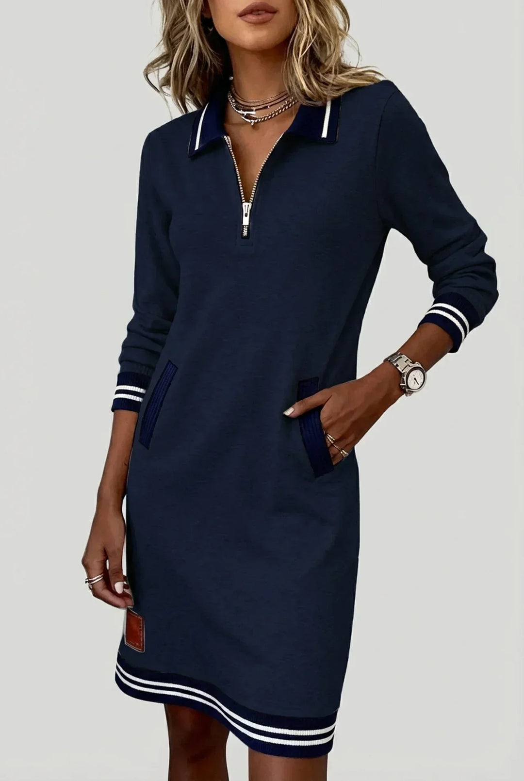Model wearing the navy blue version with white-striped collar, cuffs and hem, one hand tucked into a ribbed pocket. 3