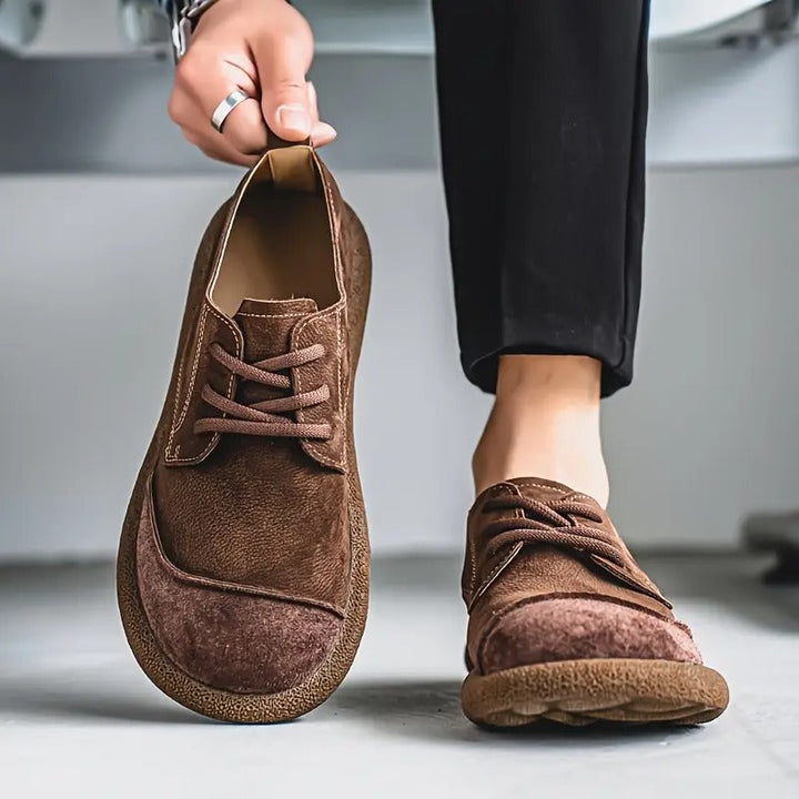 Man in black pants wears one brown leather lace-up shoe.