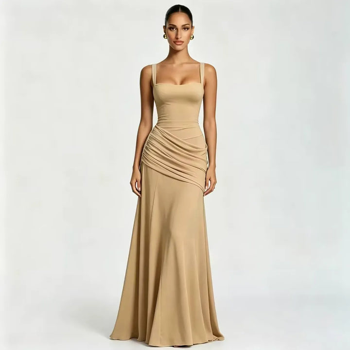 Front view of a model in a sand-beige floor-length dress with a square neckline, wide straps and draped gathers at the waist. 21