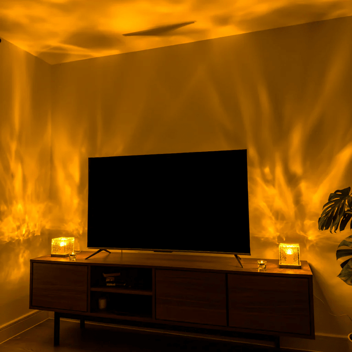 Two glowing cube lamps flank a flat-screen TV on a wooden media console, throwing warm golden light waves up the walls. 4