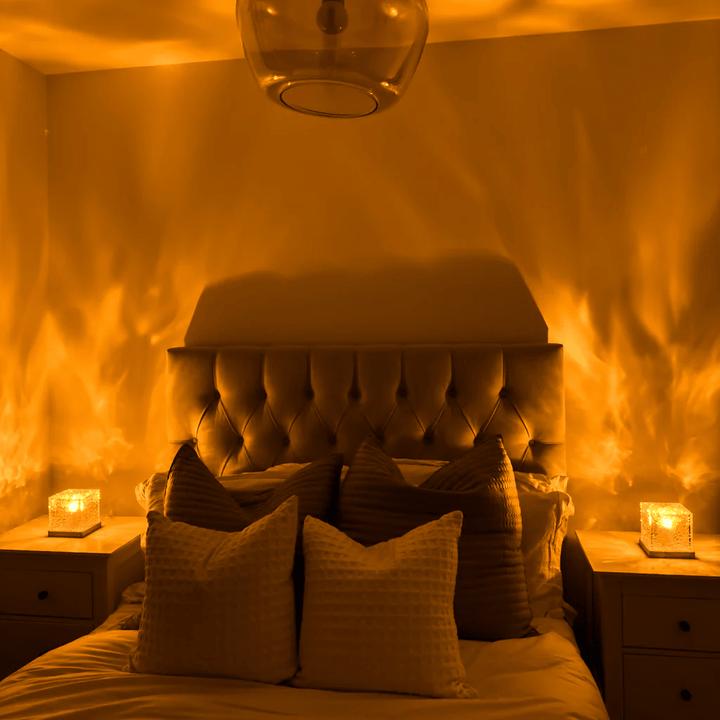 Two cube lamps on bedside tables cast flame-like amber light across the walls of a bedroom with a tufted headboard. 2