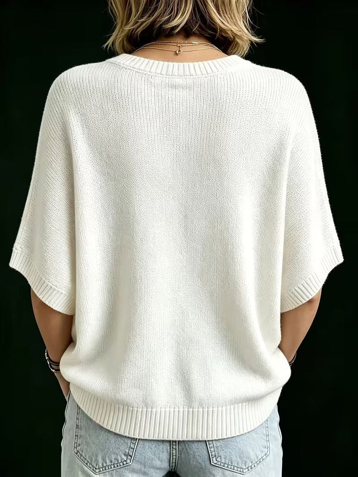Back view of the cream knit batwing top, showing the ribbed round neckline, ribbed cuffs and curved hem. 25
