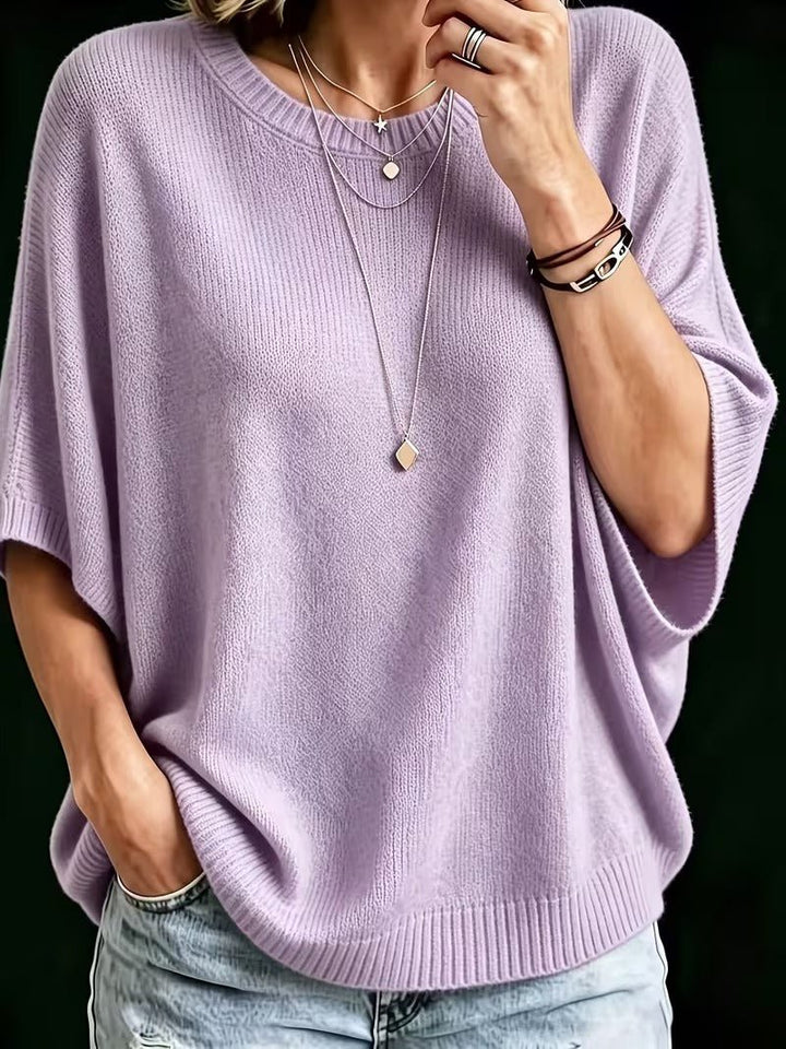 Lavender knit batwing top, close-up front view with layered necklaces and jeans.