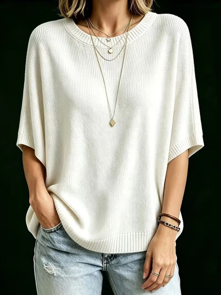 Cream relaxed knit top worn with distressed light jeans, one hand in a pocket, showing the loose batwing sleeves. 24