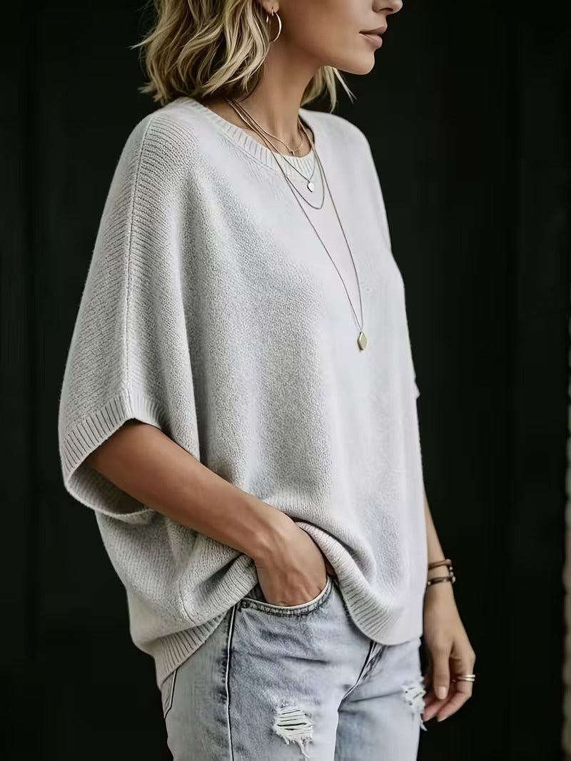 Light gray knit top, side view showing the wide batwing sleeve and ribbed hem.
