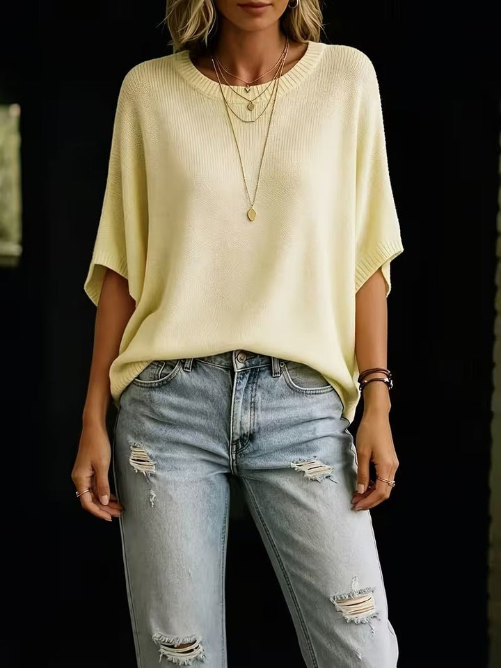Pale yellow batwing top, front view on a model paired with ripped light-wash jeans.