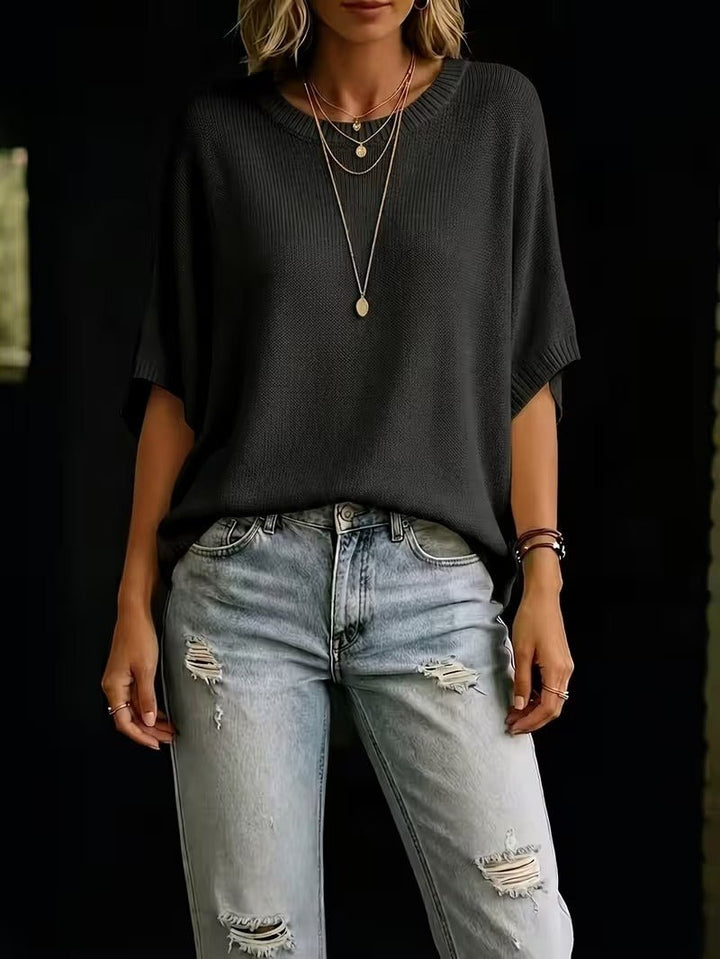 Front view of the black relaxed knit top with ripped light-wash jeans, showing the loose batwing sleeves and length. 27