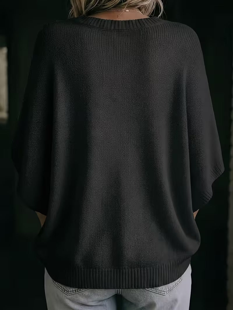 Back view of the black knit batwing top on a model, showing the smooth knit and ribbed hem. 28