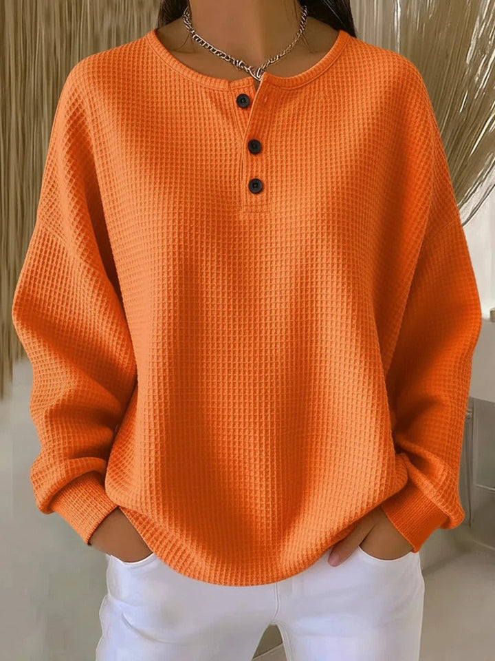 Solid orange waffle knit henley with three dark buttons and ribbed cuffs, worn with white pants 7