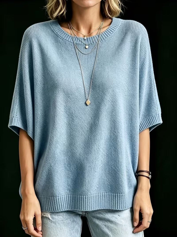 Light blue knit top in a straight front view, arms relaxed, showing the relaxed fit and ribbed hem.