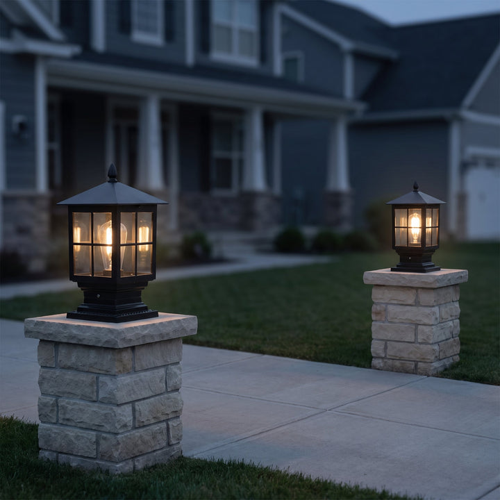 Two lit black pillar lamps on stone gateposts along a front walkway at dusk, with a gray two-story house behind. 7
