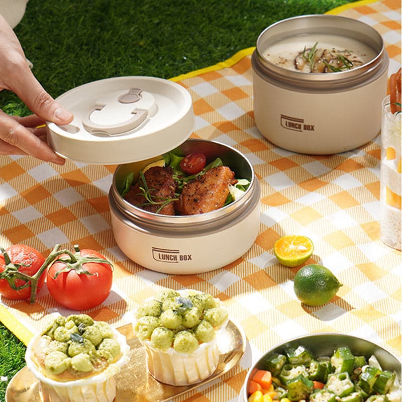 Beige container with its lid lifted, showing chicken and salad inside.