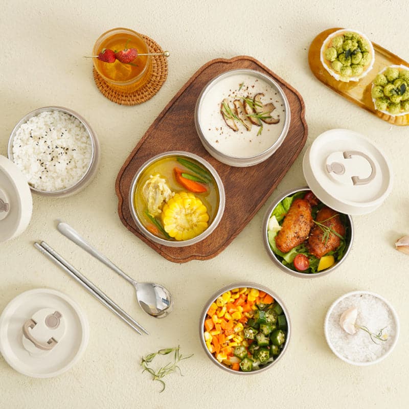 Top-down flat lay of opened containers filled with rice, soup, corn, salad and vegetables.